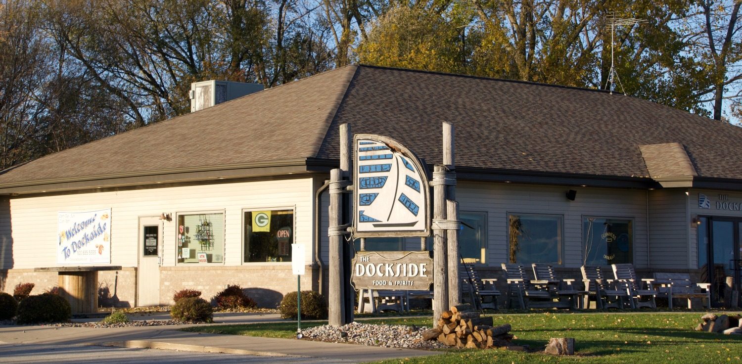 The front of The Dockside with its sign — a sailboat badge above the word DOCKSIDE — and the patio running along the building.